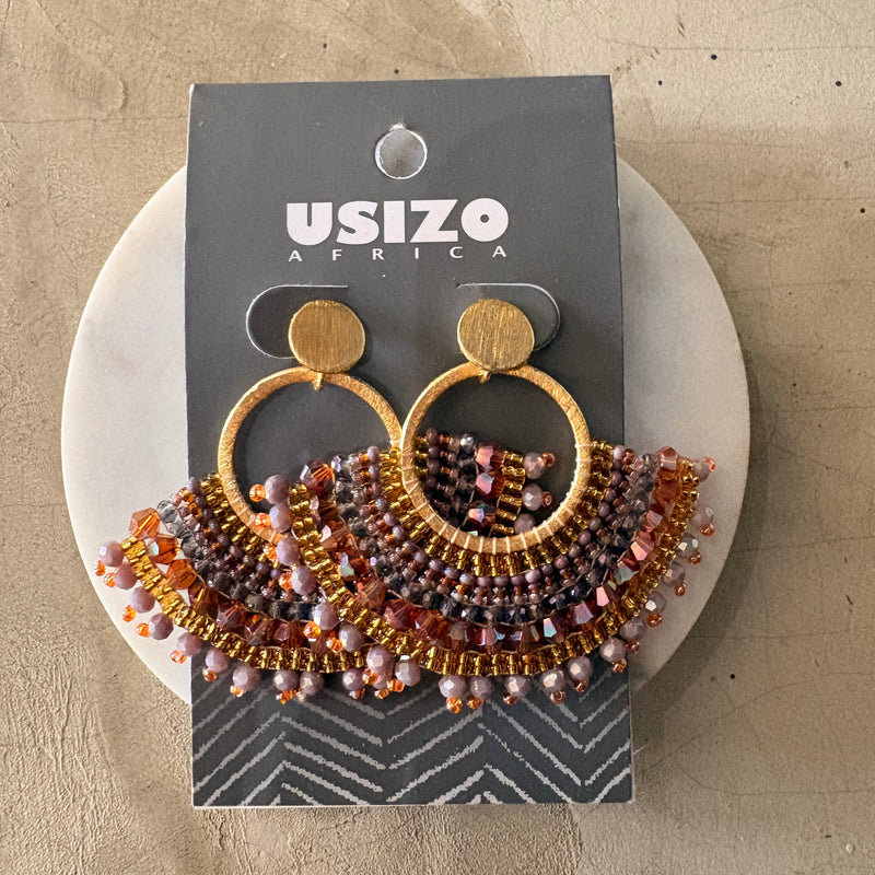 Beaded earrings on a branded card with a beige background