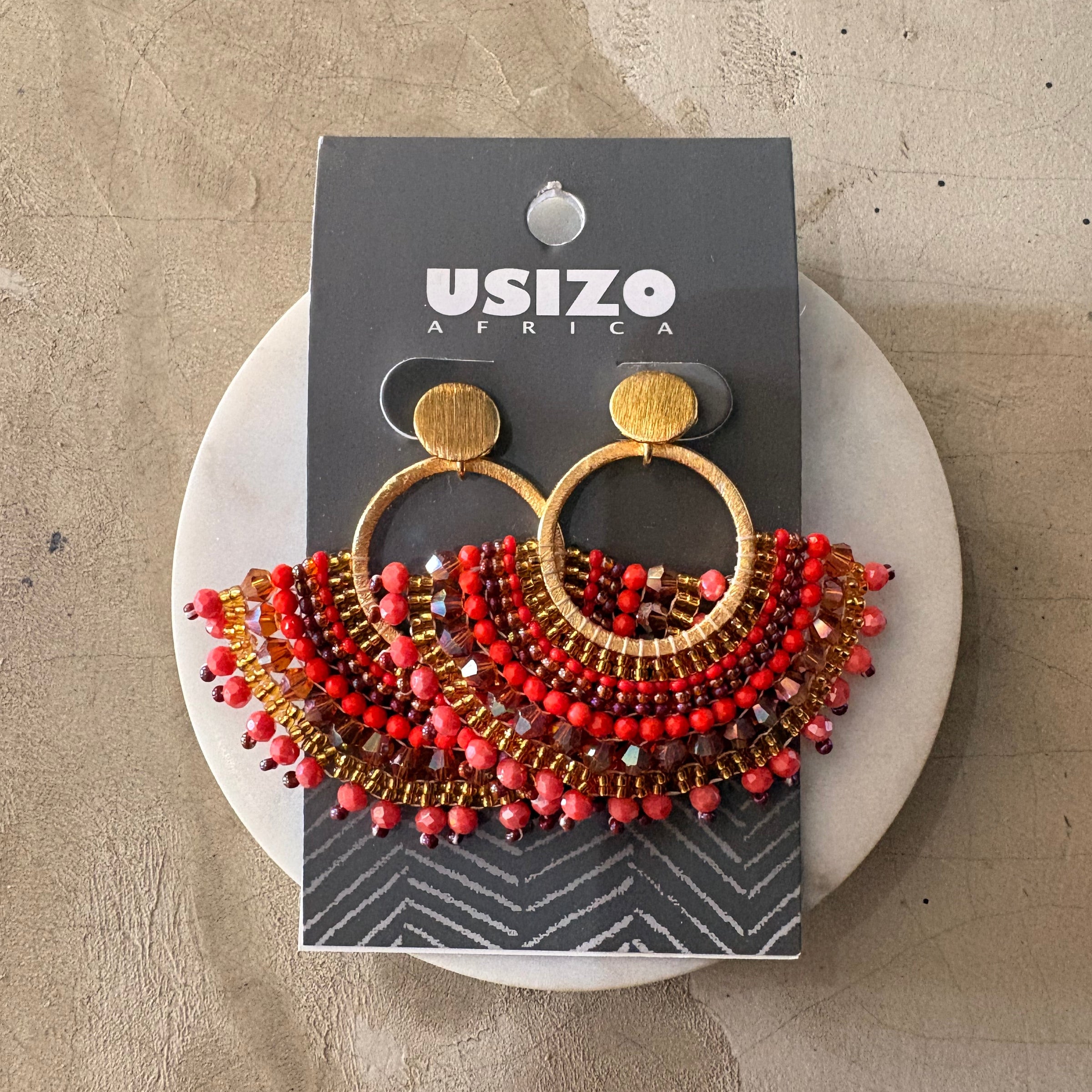 Beaded earrings on a Usizo Africa branded card against a textured beige background