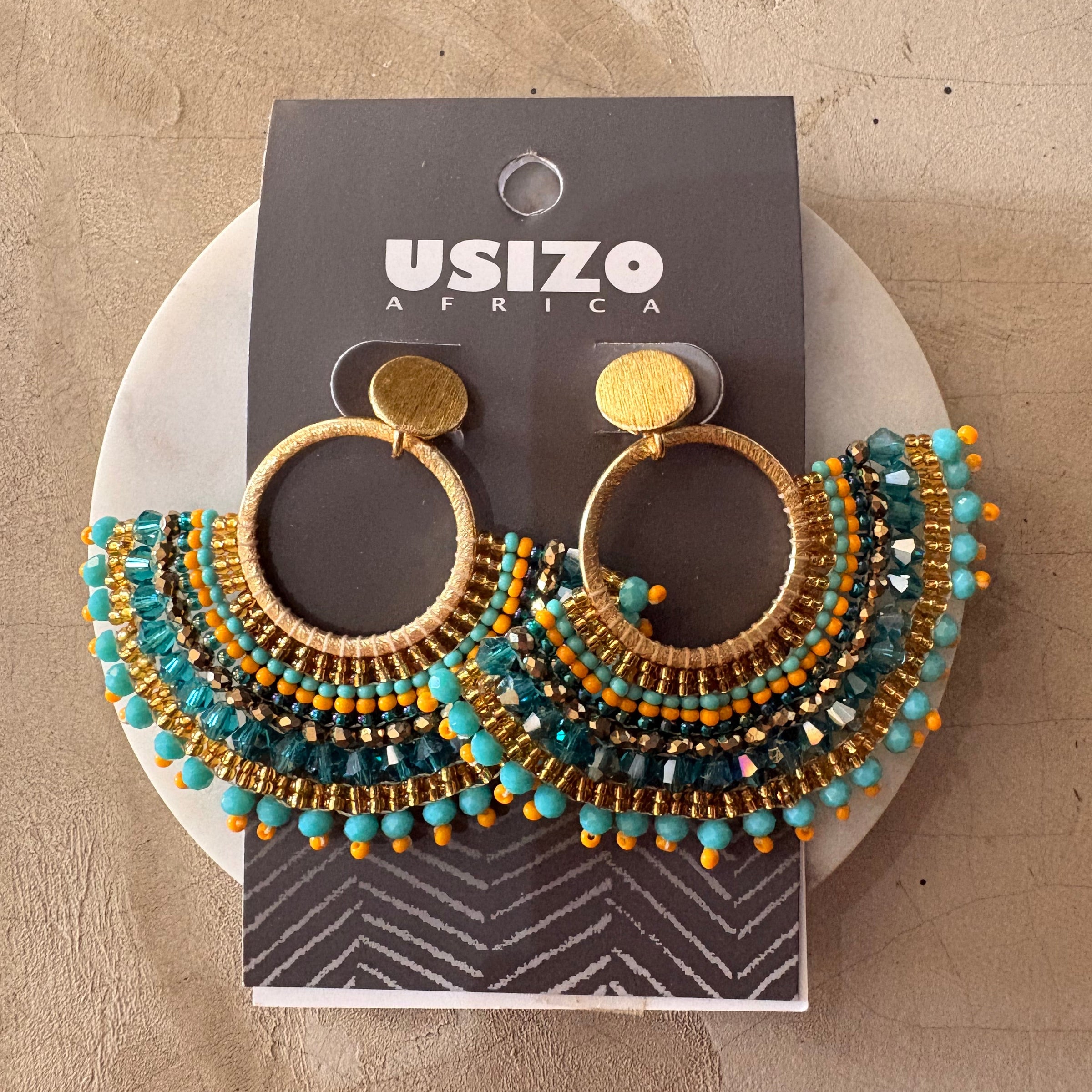 Pair of beaded earrings on a Usizo Africa branded card against a beige background