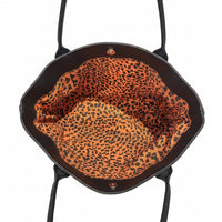 Black bag with orange leopard print lining on a light background