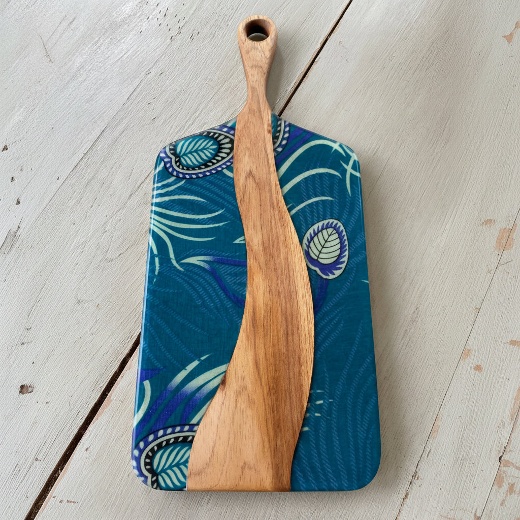 Blue patterned cutting board with a wooden paddle on a light wooden surface
