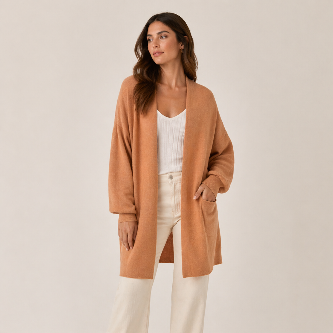 Woman wearing a clay cardigan over a white top and pants on a beige background