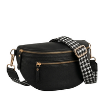 Black leather crossbody bag with a houndstooth strap on a gray background