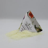 A triangular foil packet labeled 'bytholo Dark Pear' stands partly embedded in a small pile of pale yellow crystalline powder on a light gray studio background.