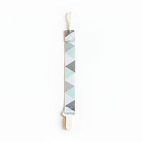 Baby pacifier clip with geometric pattern on a gray fabric background