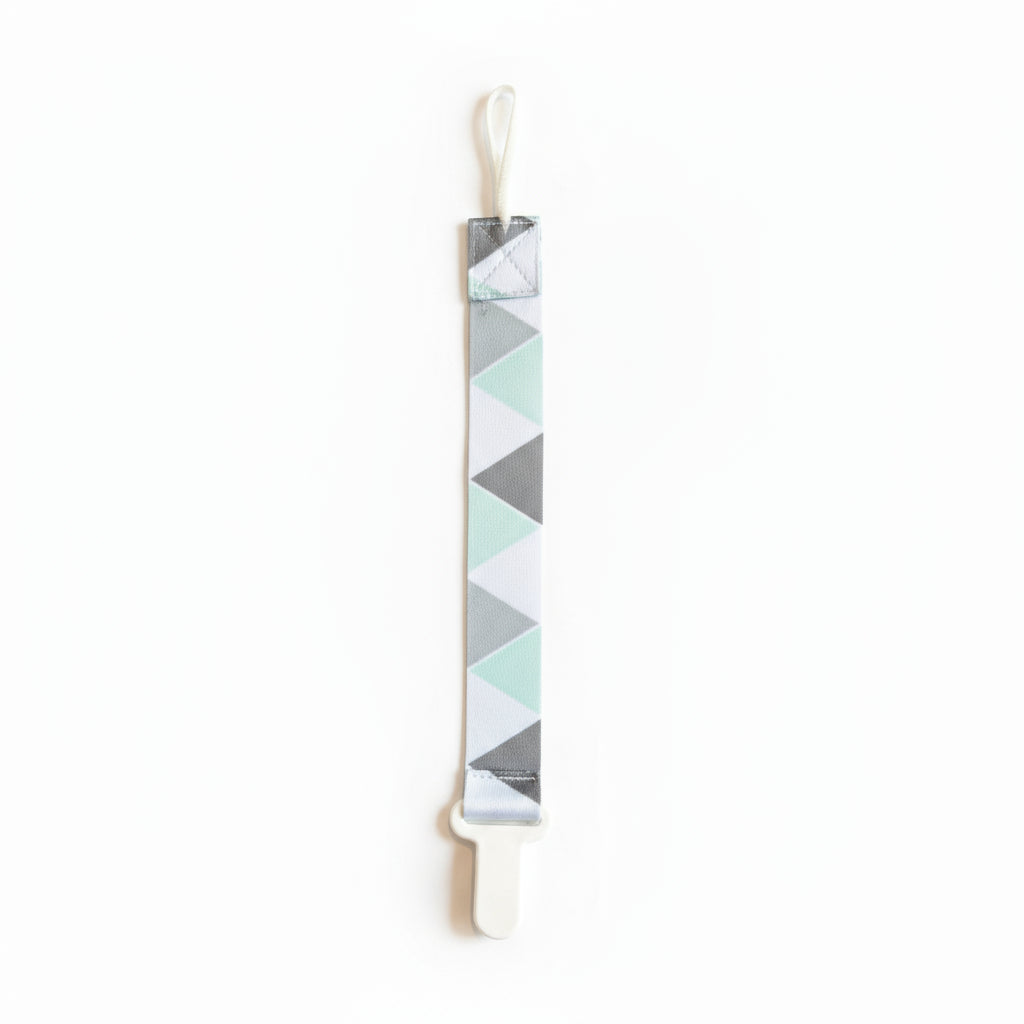Baby pacifier clip with geometric pattern on a gray fabric background
