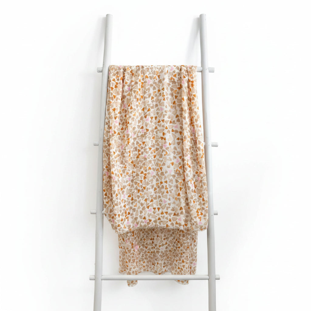 Heart-patterned fabric draped over a white ladder against a teal wall