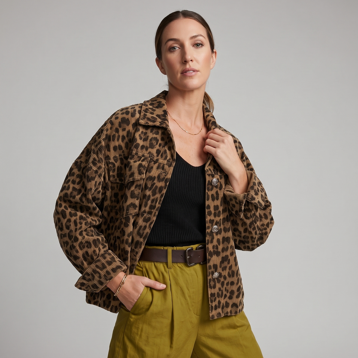 Woman wearing a leopard print jacket and green pants on a gray background
