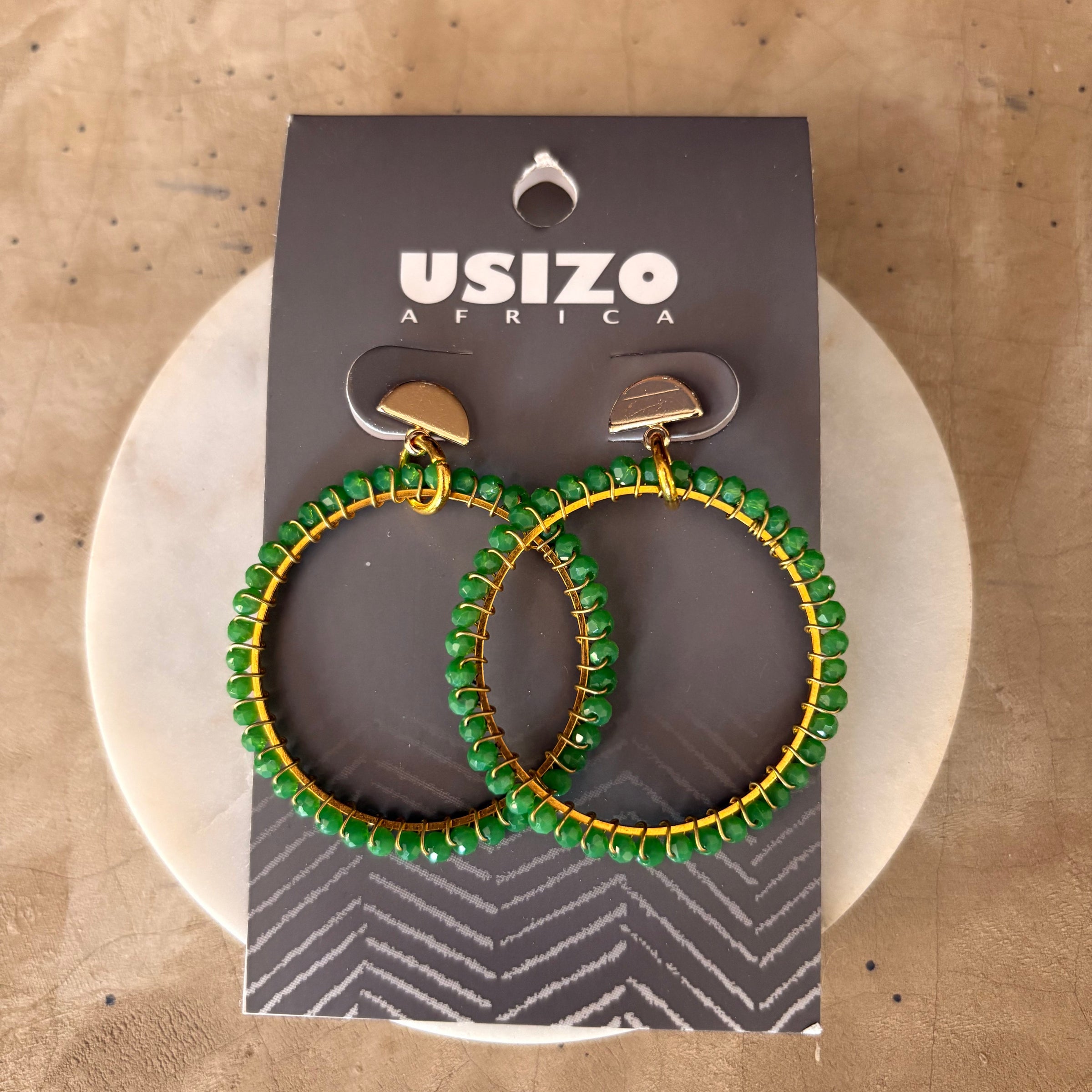 Green beaded hoop earrings on a Usizo Africa branded card against a beige background