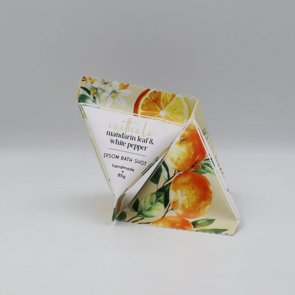 A triangular paper-style packaging display or stand featuring citrus illustrations, including mandarin oranges and white pepper, with printed text reading 'mandarin leaf & white pepper' and 'EPSON BATH SHOPS'.