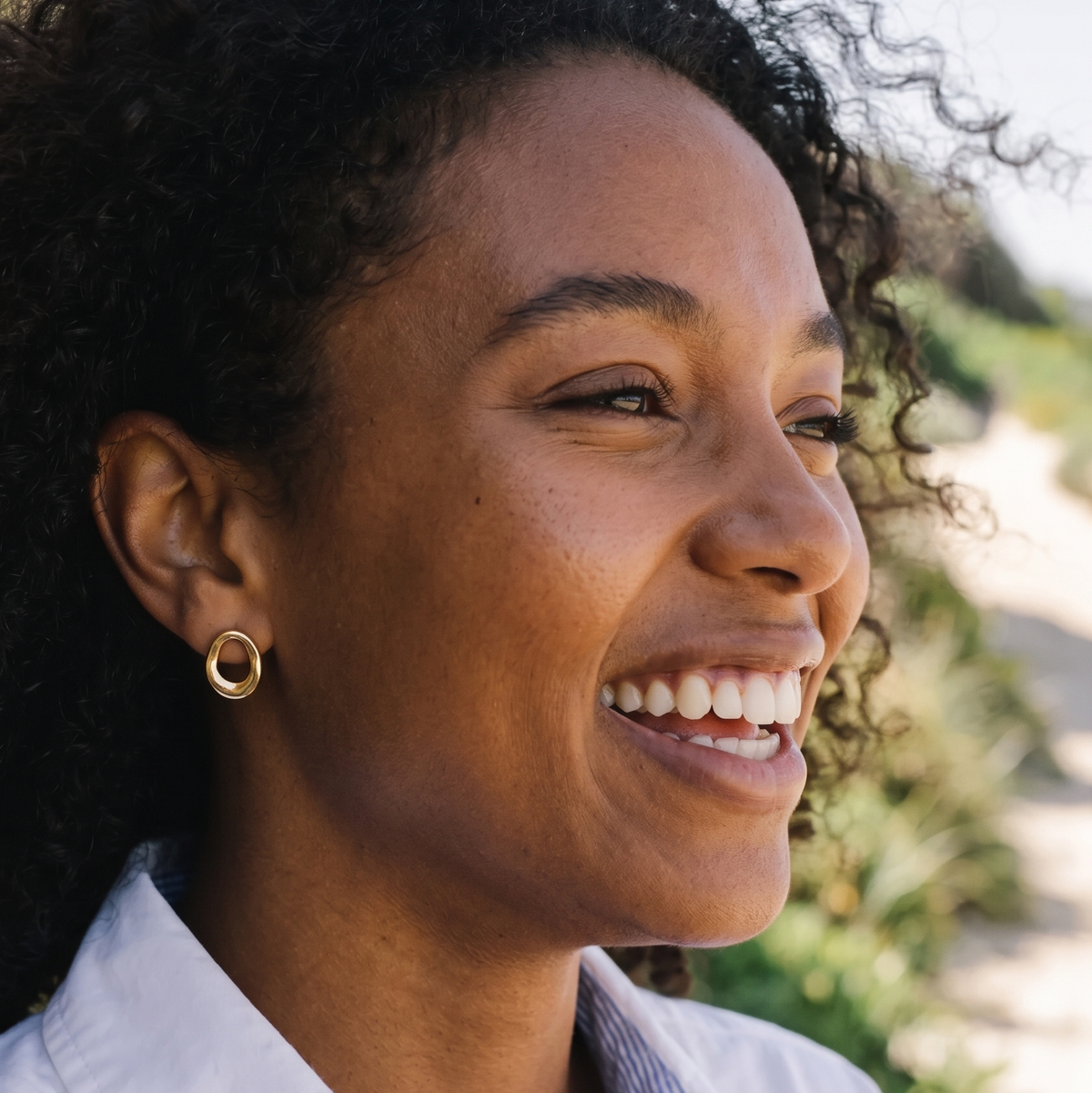 Woman smiling outdoors with a blurred natural background