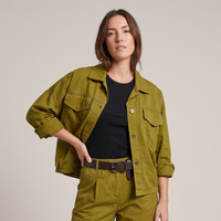 Woman wearing a green jacket and pants with a black top on a beige background