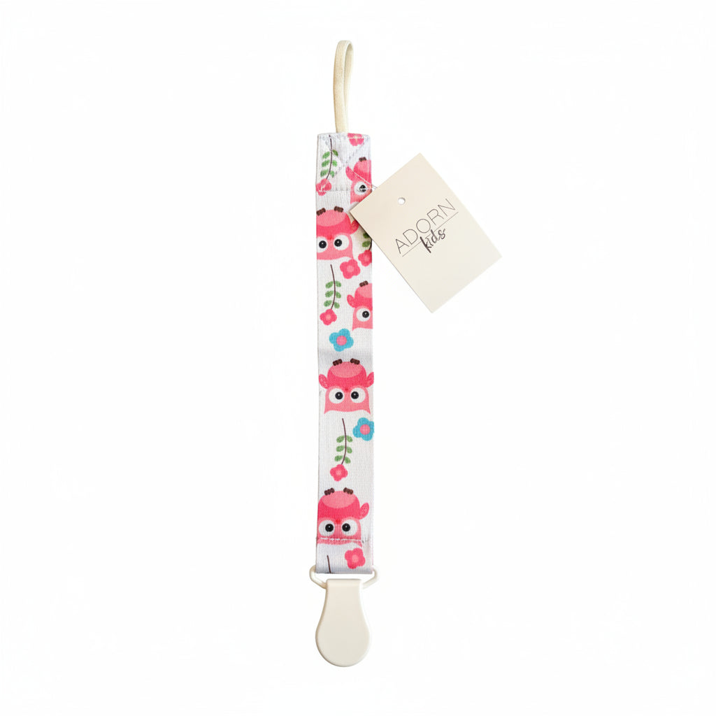 Owl-patterned baby pacifier clip on a textured surface with a visible brand tag.