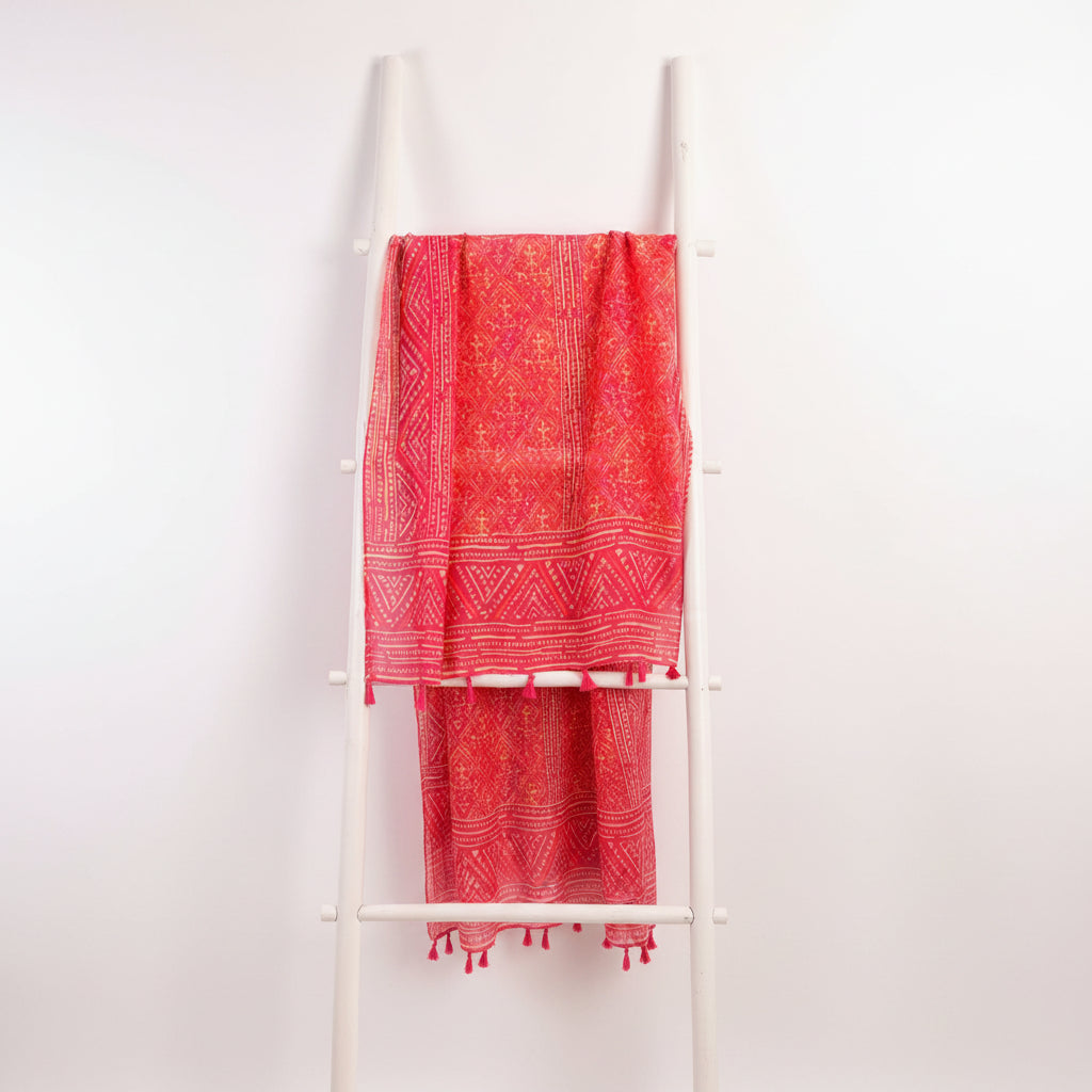 Red patterned fabric with white accents draped over a white rack against a gray background