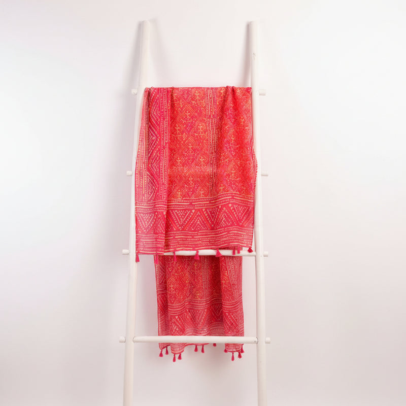 Red patterned fabric with white accents draped over a white rack against a gray background