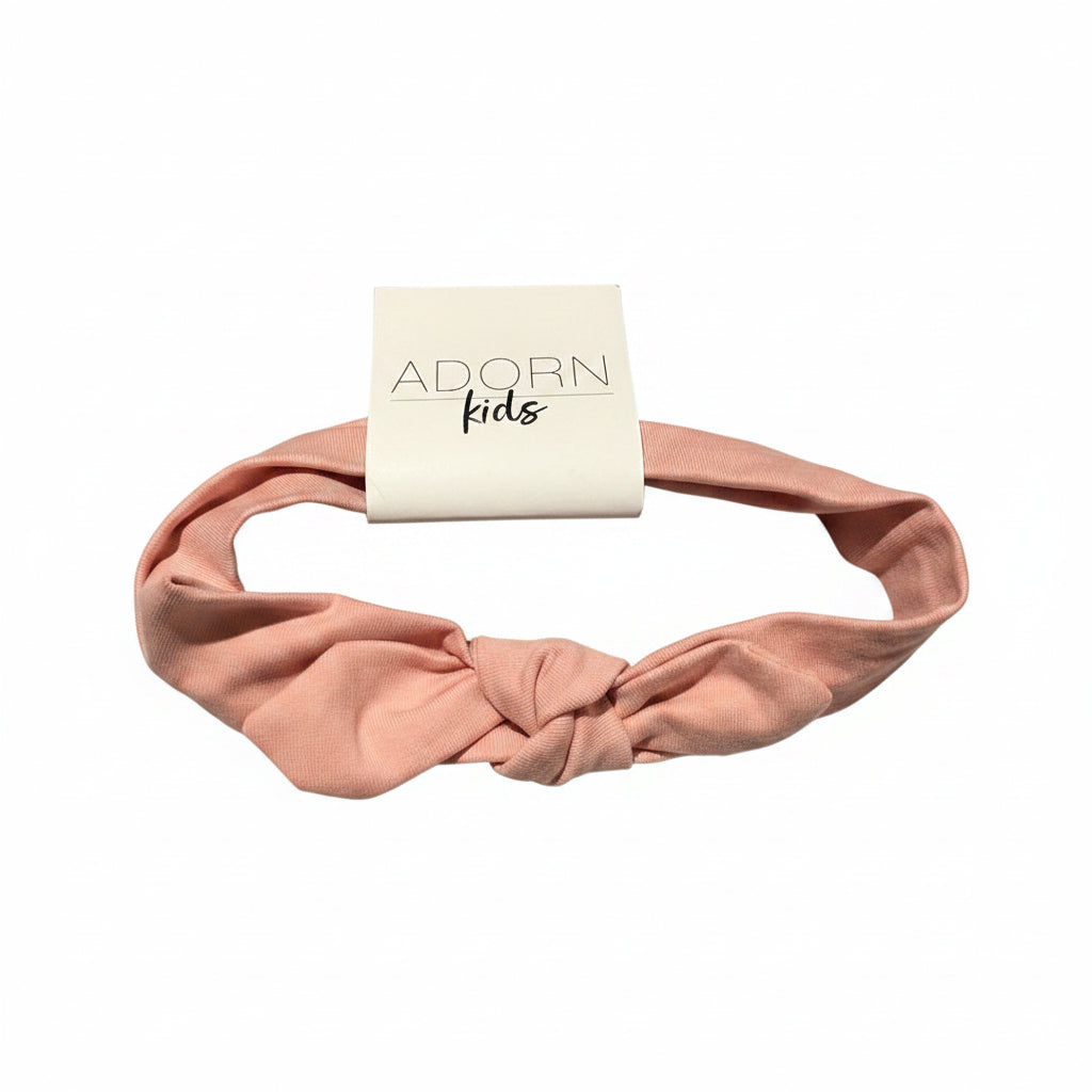 Pink headband with 'Adorn Kids' packaging on a textured surface