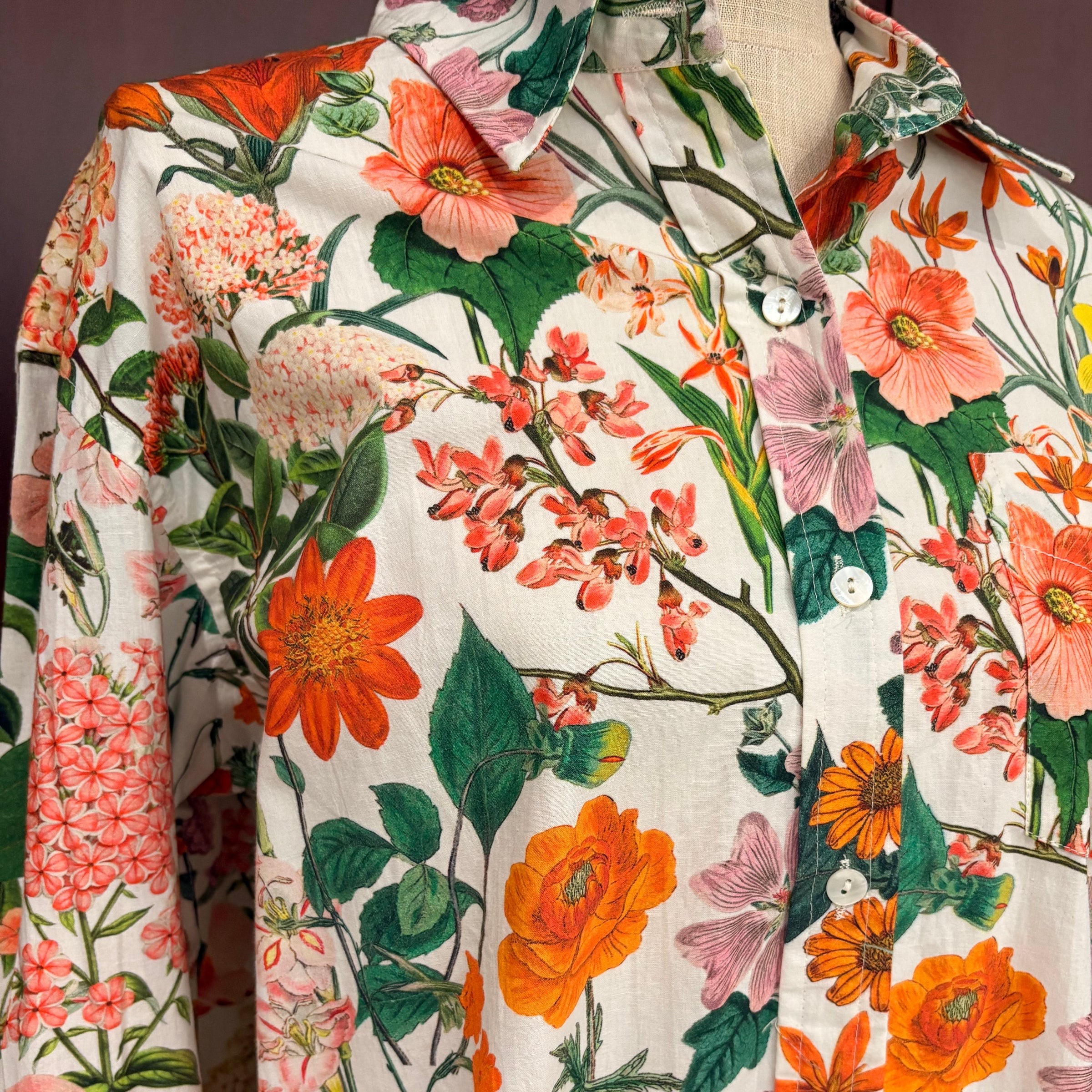 Floral patterned shirt with orange, pink, and green flowers on a white background