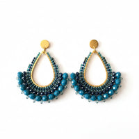 Beaded earrings on a branded card with a beige background