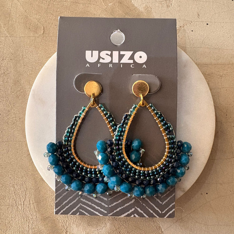 Beaded earrings on a branded card with a beige background