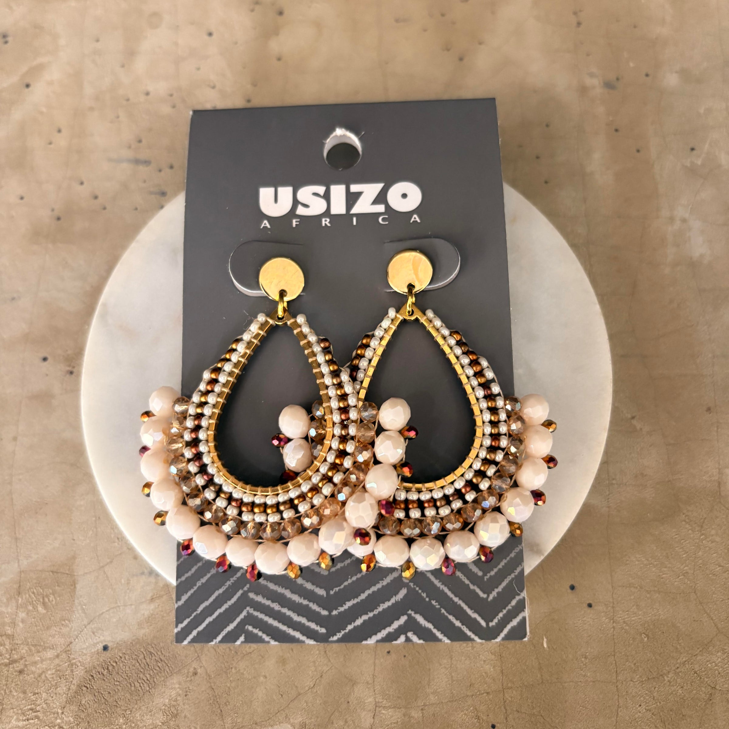 Pair of gold and beaded earrings on a 'Usizo Africa' branded card against a beige background.