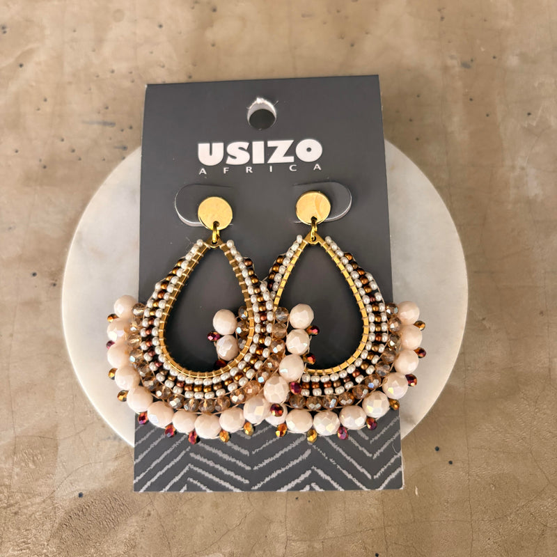 Pair of gold and beaded earrings on a 'Usizo Africa' branded card against a beige background.