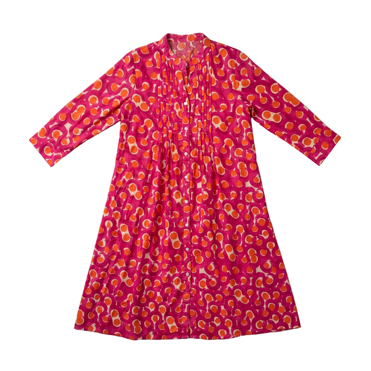 A pink long-sleeve tunic dress with an orange and yellow abstract pattern, laid flat on a light gray fabric background.